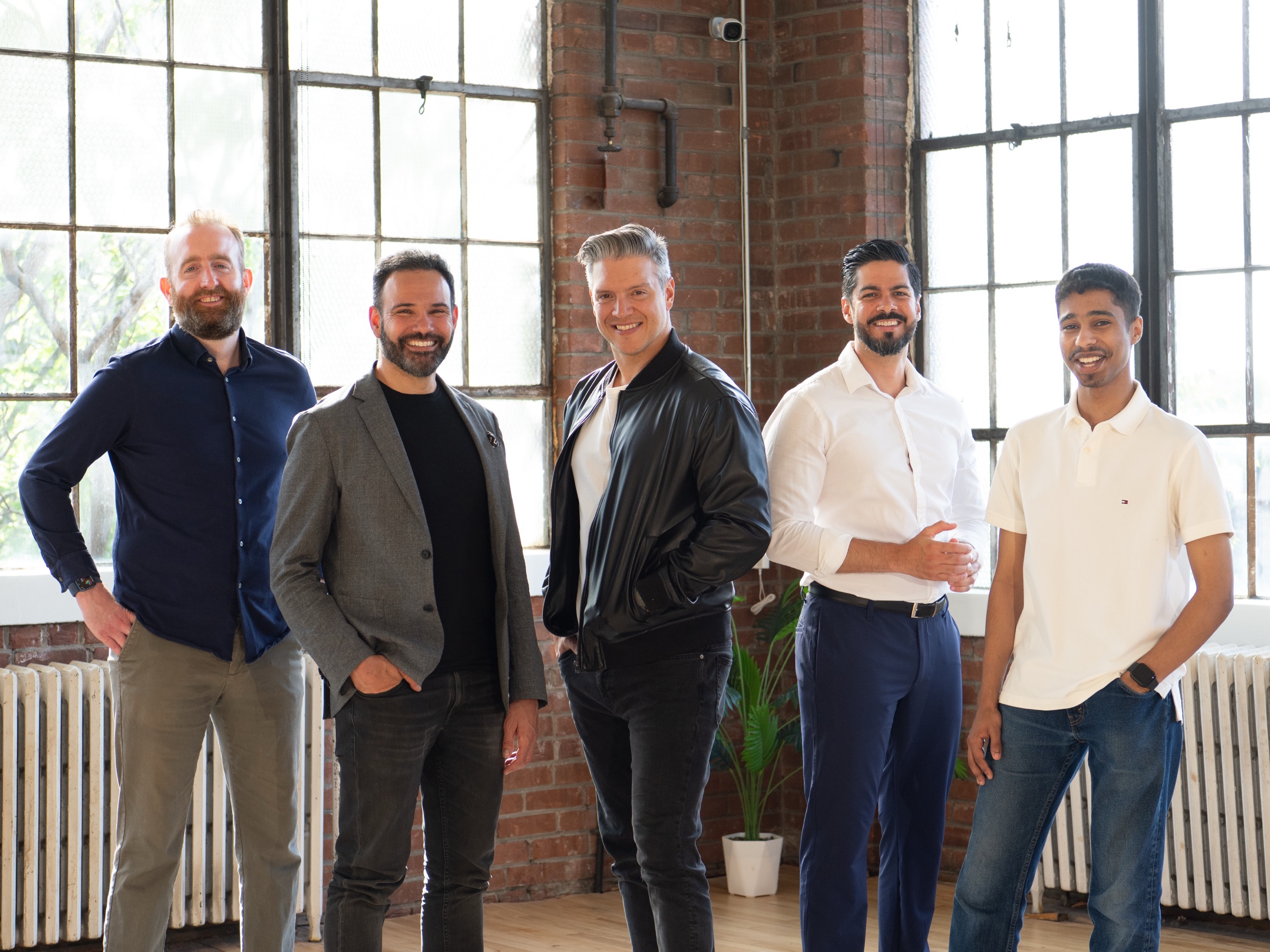The SELLIT9 team of five standing together in a sunlit industrial loft.