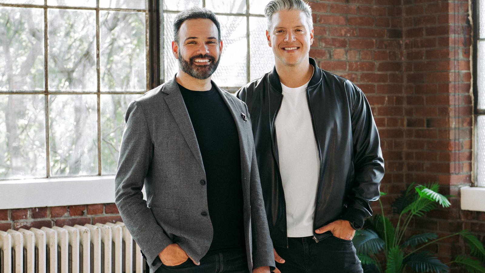 SELLIT9 co-founders Oswaldo Alvarez and Josh Guttman standing together in a brick-walled Toronto office