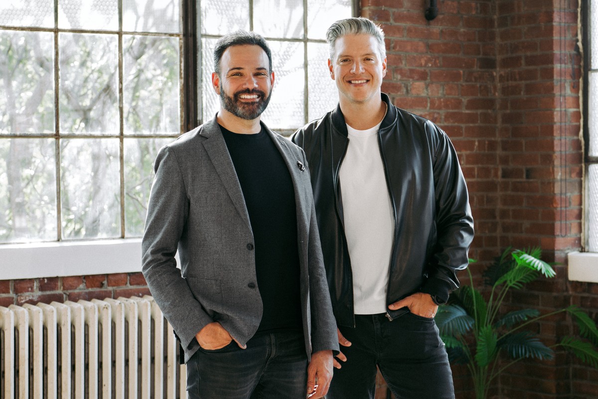 SELLIT9 co-founders Oswaldo Alvarez and Josh Guttman standing together in a brick-walled Toronto office